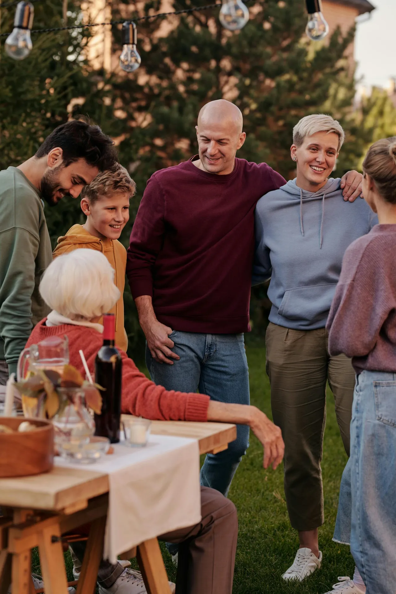 A cheerful family enjoying a sunny picnic outdoors, embracing and smiling together.