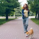 A young woman walking her Shiba Inu in an urban park, enjoying a relaxing day.