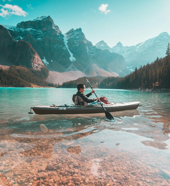 A lone kayaker paddles on the serene waters of Moraine Lake with stunning mountain scenery in Banff, Alberta.