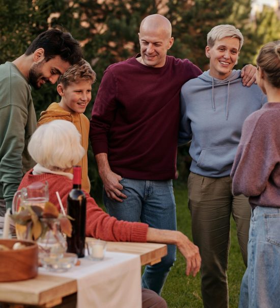 A cheerful family enjoying a sunny picnic outdoors, embracing and smiling together.